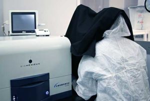 Scan RDI machine - A computer on the left, and a person under a black hood performing analytical testing